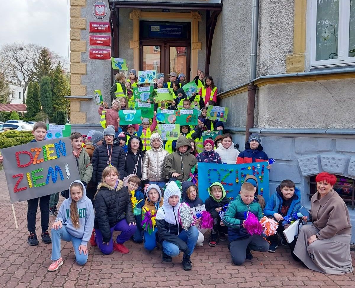 Dzieci na schodach przed urzędem, trzymają kolorowe plakaty o ziemi