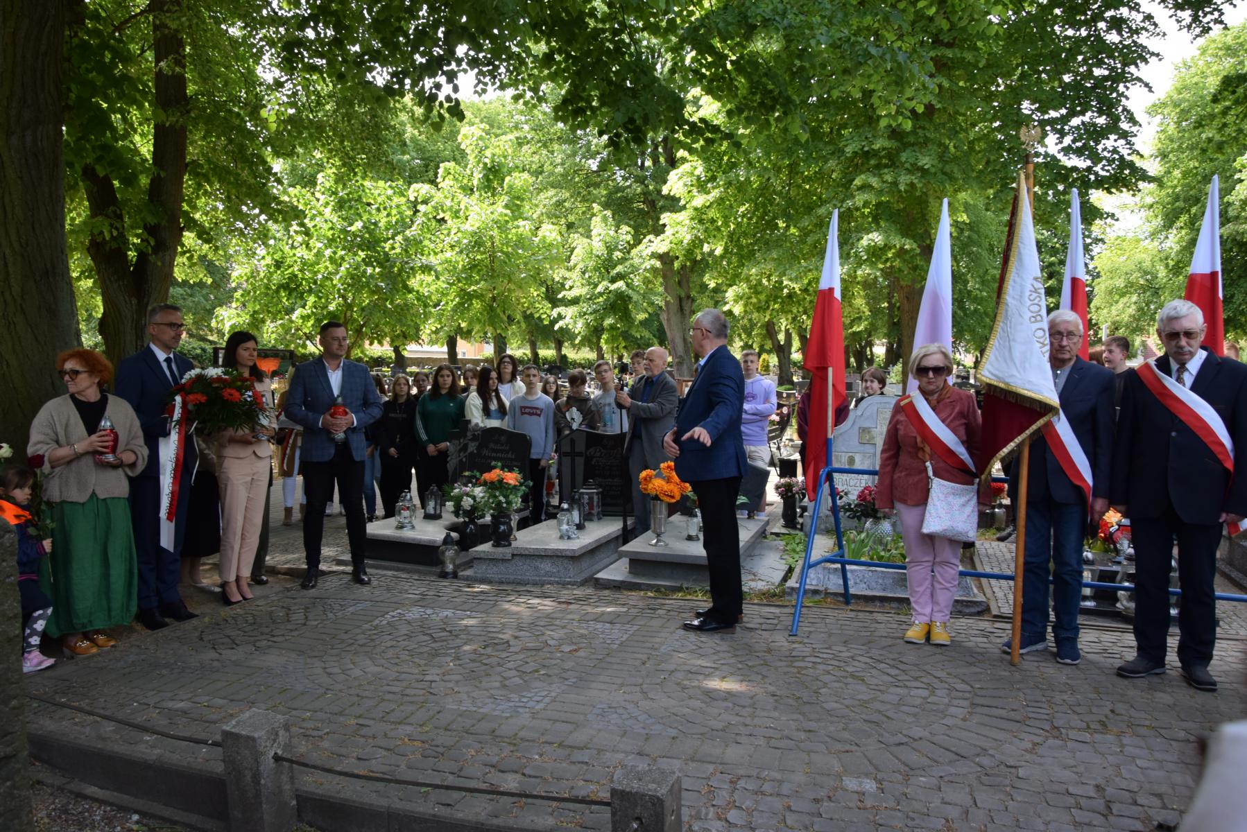 Uczestnicy stoją na cmentarzu wokół grobu Nieznanego Żołnierza 