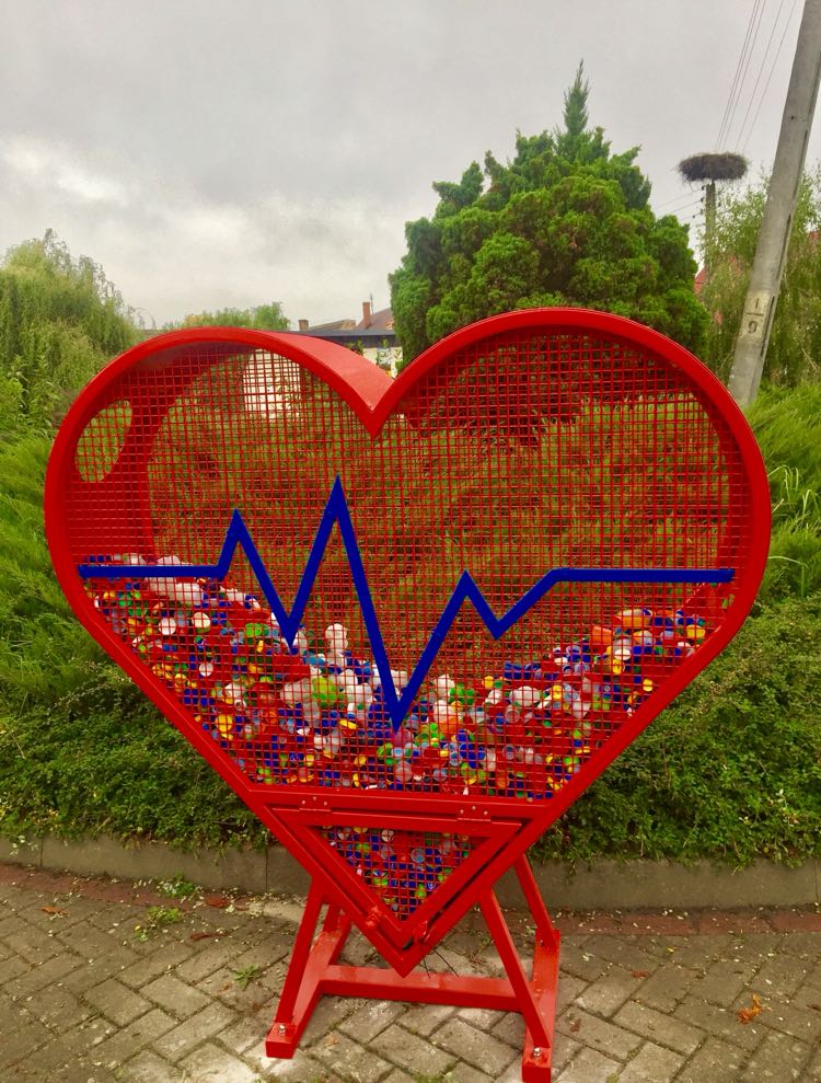 Powiększ zdjęcie. Pojemnik metalowy czerwony w kształcie serca, wypełniony nakrętkami