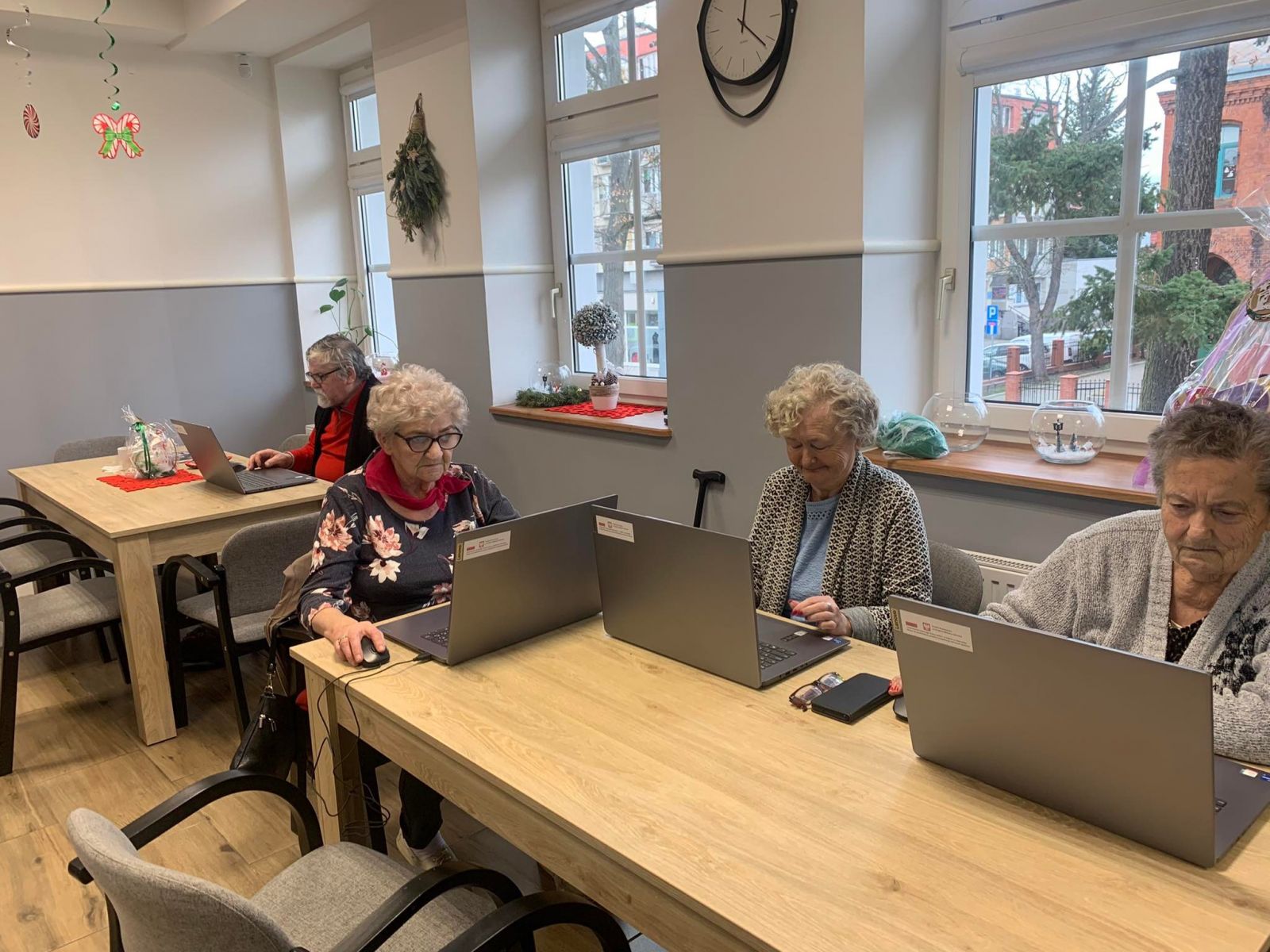 Seniorzy siedzą przy komputerach